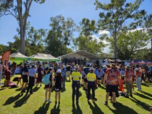 An image of a large crowd of people standing outside in the sunshine watching Darumbal NAIDOC week celebrations