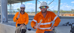 An image of two FGP team members wearing high visability clothing, each eating a Hydrolyte ice pole while taking a break on the project site to stay hydrated.